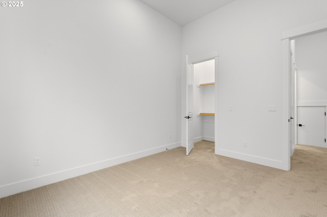 unfurnished bedroom with a walk in closet, light colored carpet, and a closet