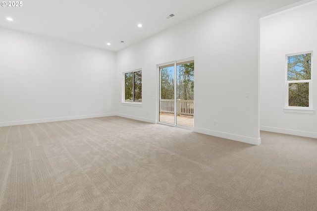 carpeted spare room featuring a high ceiling