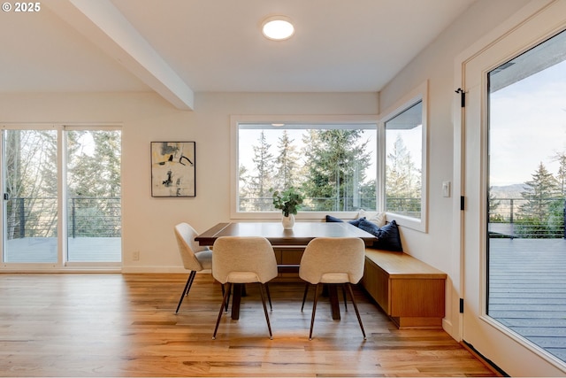 dining space with light hardwood / wood-style flooring, beamed ceiling, and breakfast area