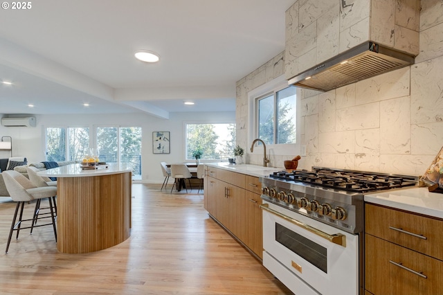 kitchen featuring a wall mounted air conditioner, high end white range oven, sink, a center island, and a breakfast bar area