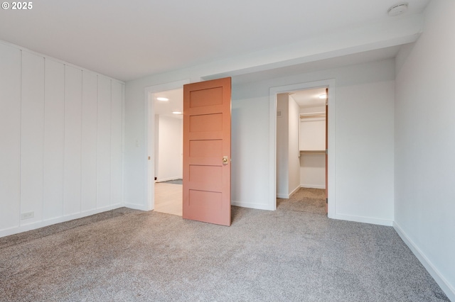 unfurnished bedroom with a walk in closet, light carpet, and a closet