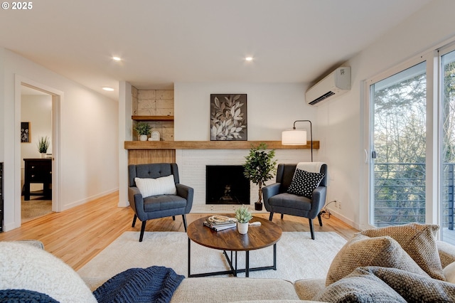 living room with a fireplace, light wood-type flooring, and a wall mounted AC