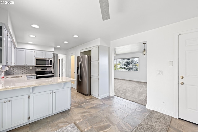 kitchen with stainless steel appliances, tasteful backsplash, a sink, a peninsula, and baseboards