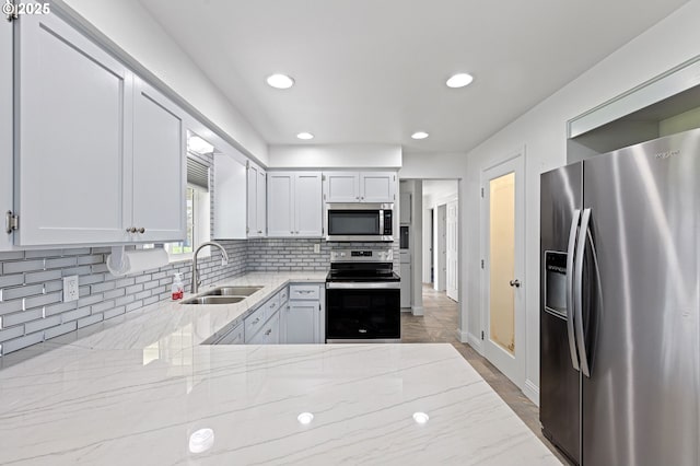 kitchen featuring appliances with stainless steel finishes, backsplash, a sink, and light stone countertops