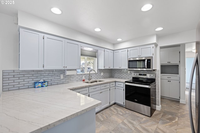 kitchen featuring recessed lighting, a sink, appliances with stainless steel finishes, light stone countertops, and tasteful backsplash