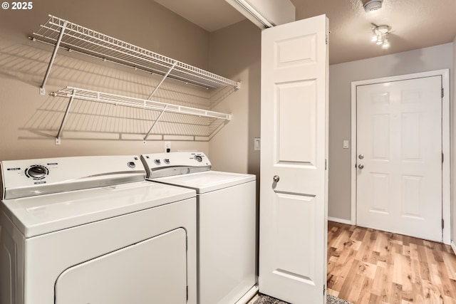 clothes washing area with separate washer and dryer and light hardwood / wood-style floors