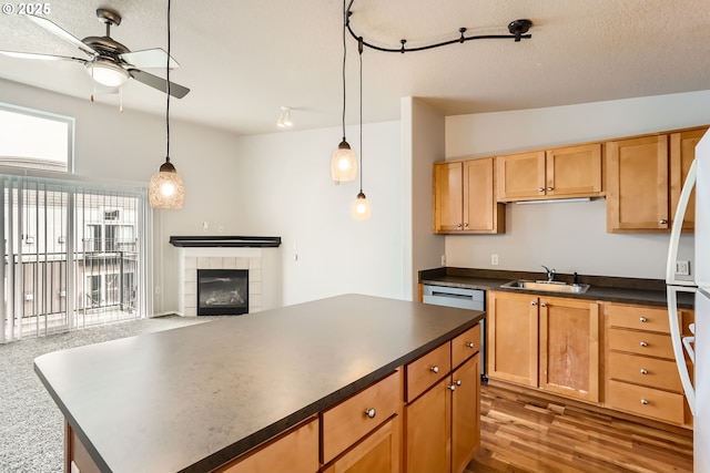 kitchen featuring a tile fireplace, ceiling fan, sink, and pendant lighting