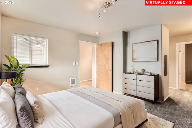 carpeted bedroom featuring electric panel and track lighting