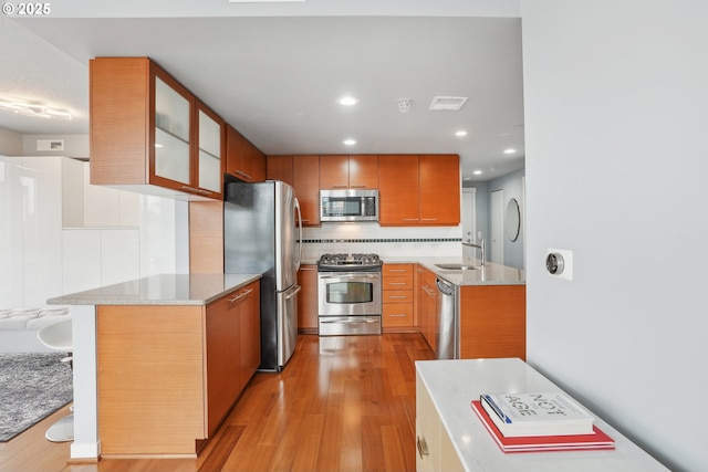 kitchen featuring visible vents, a sink, decorative backsplash, light wood-style floors, and appliances with stainless steel finishes