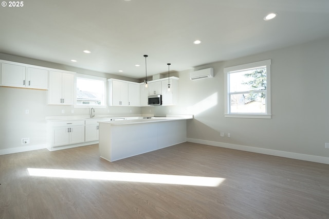 kitchen with pendant lighting, sink, a wall unit AC, white cabinets, and kitchen peninsula