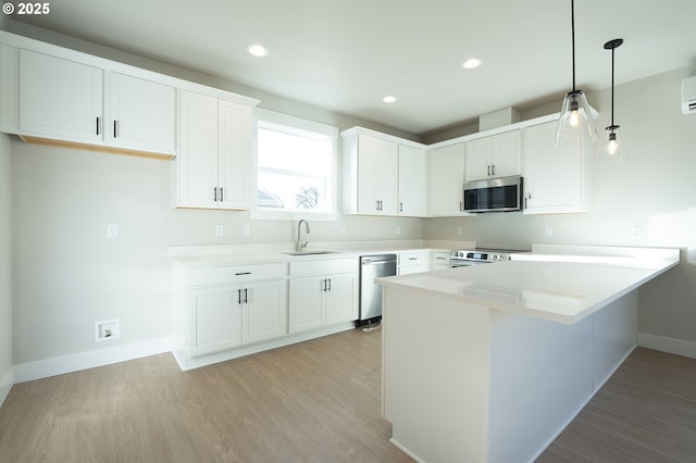 kitchen with sink, white cabinetry, hanging light fixtures, light hardwood / wood-style flooring, and stainless steel appliances