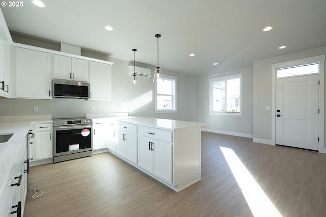 kitchen featuring appliances with stainless steel finishes, kitchen peninsula, a wall mounted air conditioner, and white cabinets