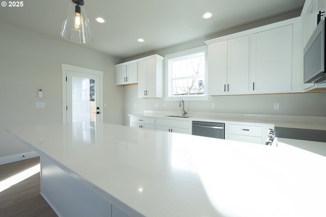 kitchen featuring hanging light fixtures, dishwasher, sink, and white cabinetry