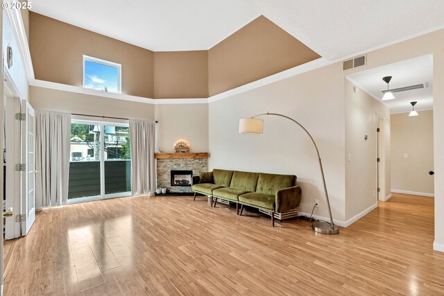 4320 S Corbett Ave Unit 302, Portland, OR 97239 - living room with baseboards, light wood-style floors, a high ceiling, a stone fireplace, and crown molding