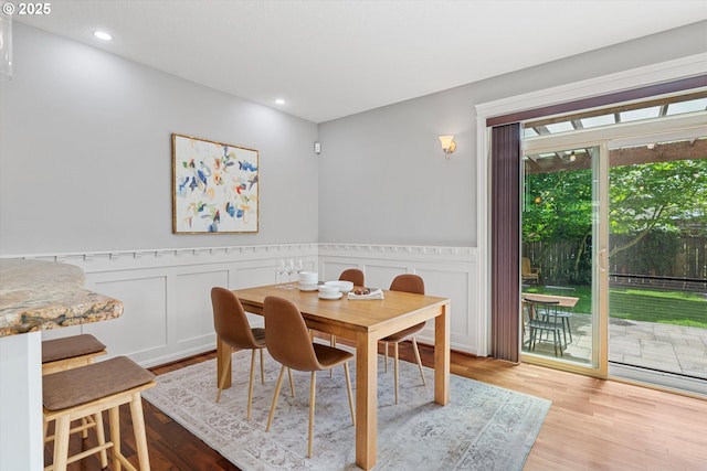 dining room featuring wood finished floors, a wainscoted wall, recessed lighting, and a decorative wall