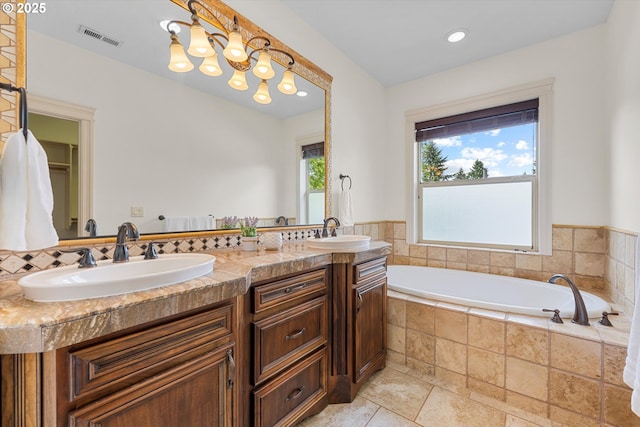full bath with a garden tub, double vanity, stone tile flooring, and recessed lighting