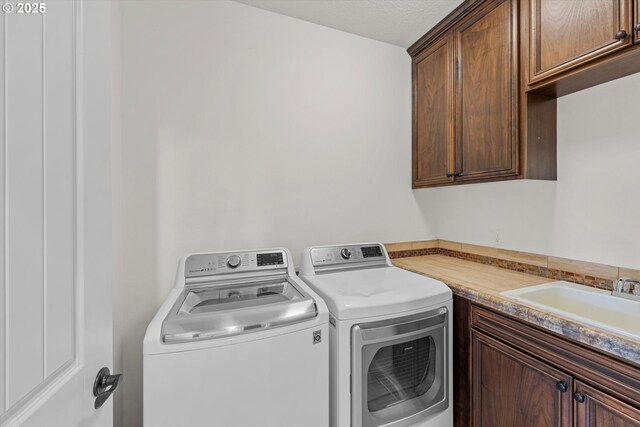 clothes washing area with washer and dryer and cabinet space