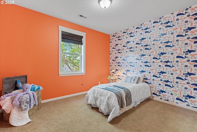 bedroom featuring carpet floors, an accent wall, a textured ceiling, baseboards, and wallpapered walls