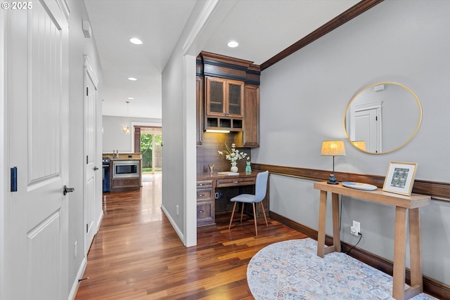corridor with wood finished floors, recessed lighting, an office area, baseboards, and ornamental molding