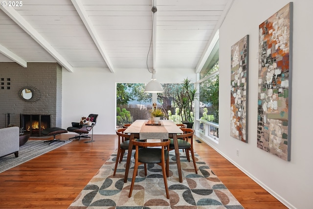 311 NE 130th Pl, Portland, OR 97230 - dining room featuring healthy amount of natural light, beamed ceiling, a brick fireplace, wood finished floors, and baseboards