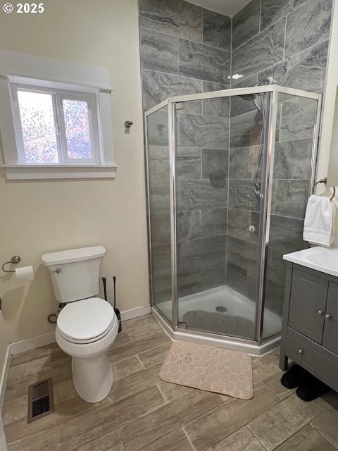 bathroom featuring an enclosed shower, vanity, and toilet