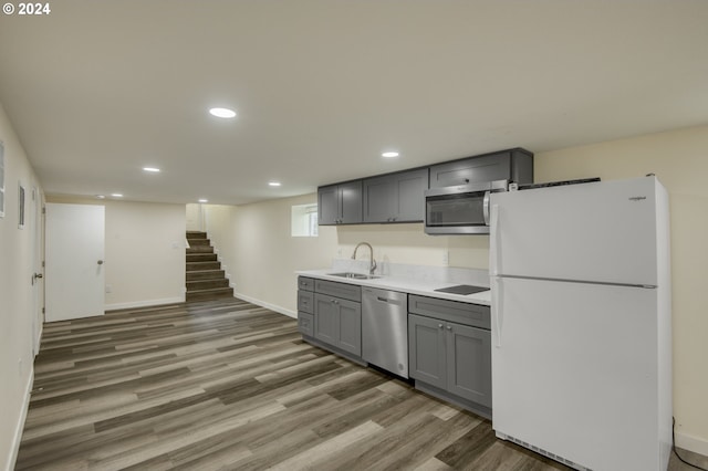 kitchen with stainless steel appliances, sink, gray cabinetry, and dark hardwood / wood-style floors