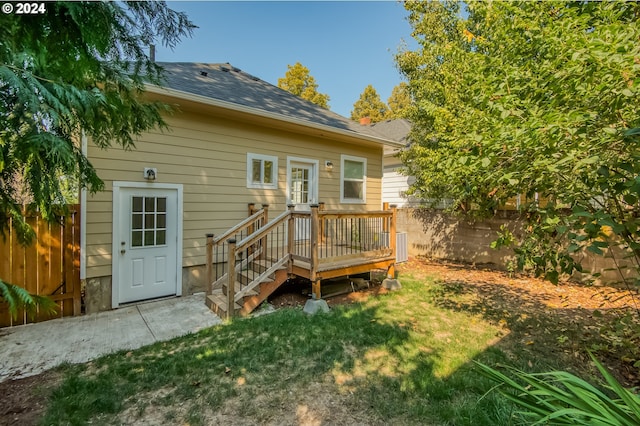 rear view of house featuring a wooden deck and a yard