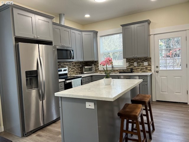 kitchen featuring tasteful backsplash, appliances with stainless steel finishes, a center island, and gray cabinets