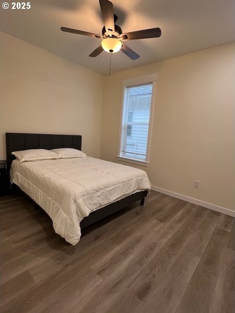 bedroom with dark hardwood / wood-style flooring and ceiling fan