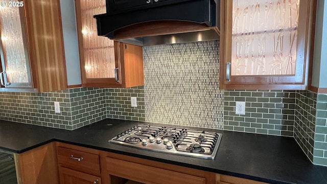 2917 NE 9th Ave, Portland, OR 97212 - kitchen with stainless steel gas cooktop, custom range hood, dark countertops, decorative backsplash, and brown cabinetry