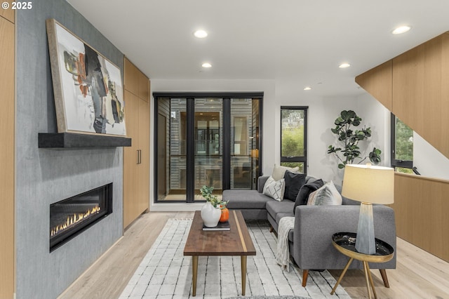 living room featuring a fireplace, light hardwood / wood-style flooring, and a wealth of natural light