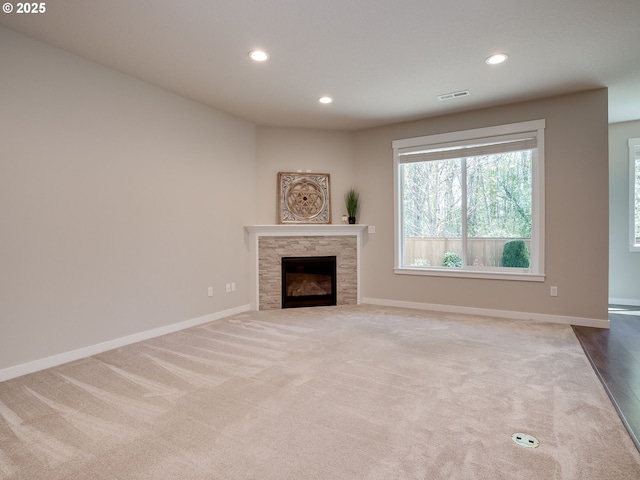unfurnished living room with visible vents, a fireplace, recessed lighting, and carpet flooring