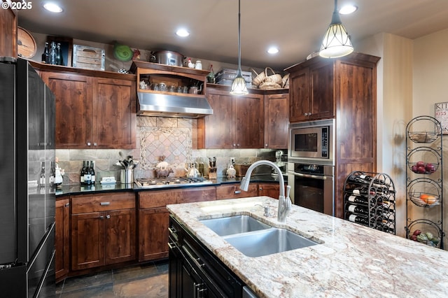 kitchen featuring decorative backsplash, hanging light fixtures, range hood, stainless steel appliances, and a sink