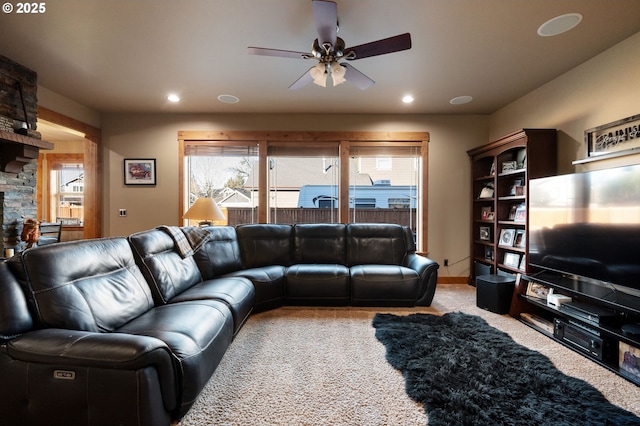 carpeted living room with a ceiling fan, recessed lighting, a stone fireplace, and baseboards