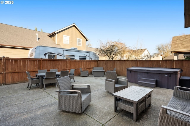 view of patio with outdoor dining area, a fenced backyard, and a hot tub