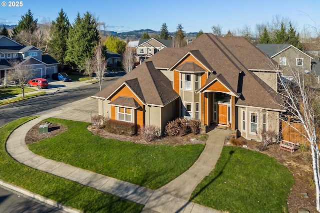 traditional-style home with a shingled roof, a residential view, fence, and a front yard