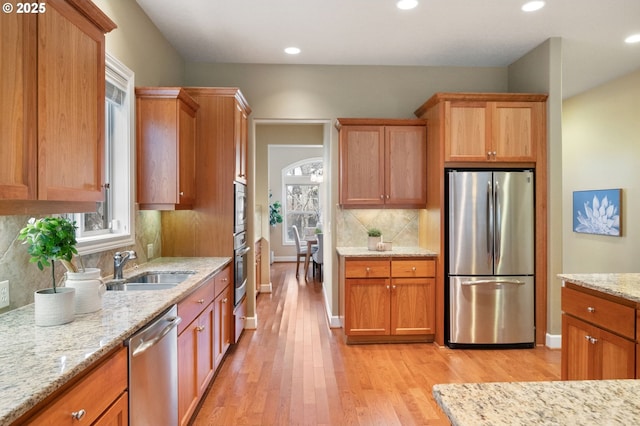 kitchen featuring sink, light hardwood / wood-style flooring, light stone countertops, and appliances with stainless steel finishes