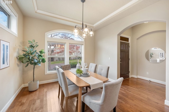 dining room with plenty of natural light, light hardwood / wood-style flooring, and a tray ceiling