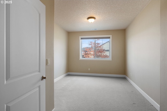 empty room featuring light colored carpet and a textured ceiling