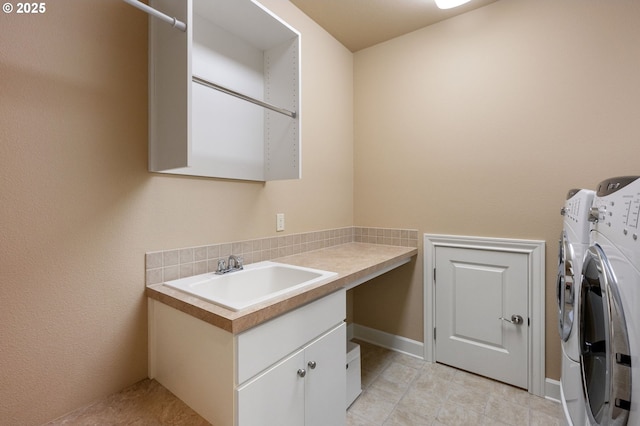 clothes washing area with cabinets, sink, and washing machine and clothes dryer