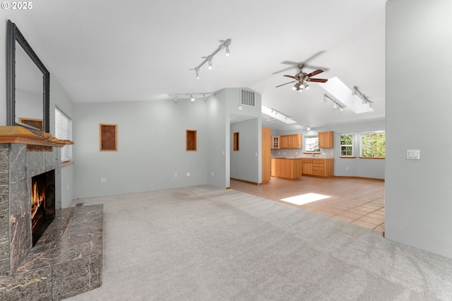 unfurnished living room featuring a fireplace, a ceiling fan, rail lighting, and lofted ceiling