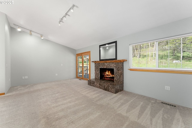 unfurnished living room featuring visible vents, rail lighting, carpet floors, and a premium fireplace