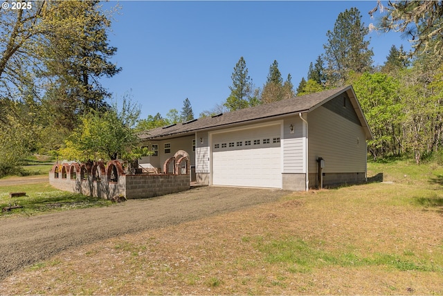 view of side of property with an attached garage and dirt driveway