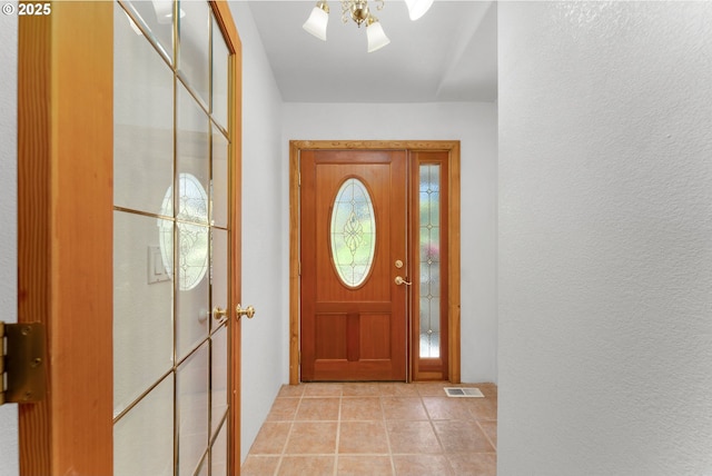 entryway with visible vents, a ceiling fan, a textured wall, and light tile patterned floors