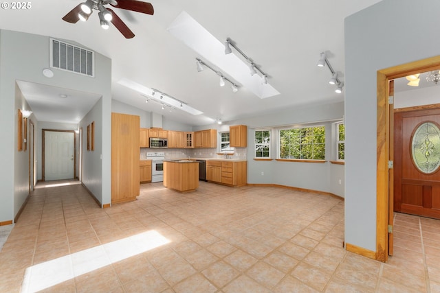 kitchen featuring visible vents, baseboards, white electric range, a center island, and stainless steel microwave