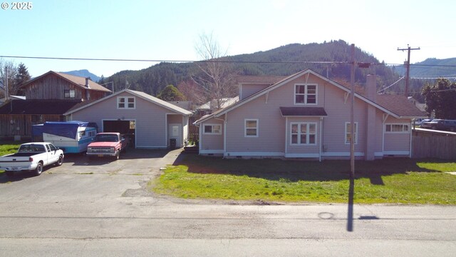 view of front of house with aphalt driveway, a mountain view, and a front lawn