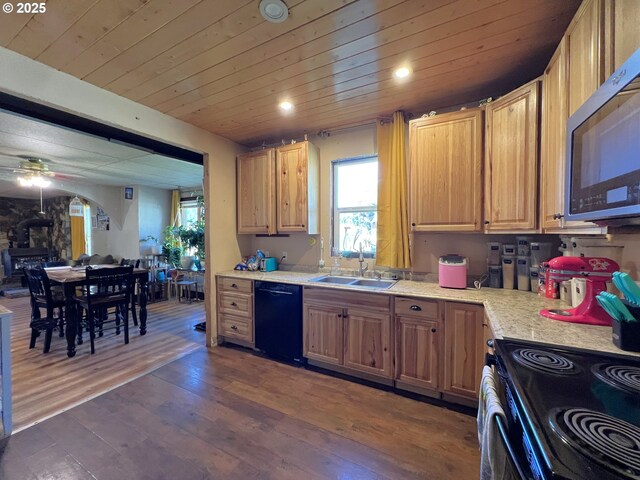 kitchen featuring black dishwasher, dark wood finished floors, stainless steel microwave, light countertops, and a sink