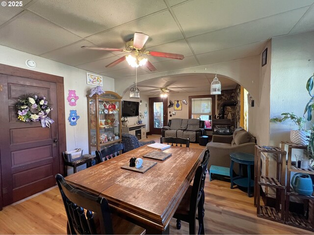 dining room with a wood stove, light wood finished floors, and a drop ceiling