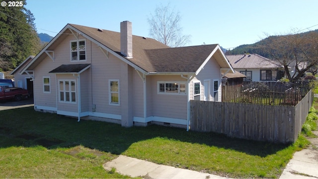 exterior space featuring fence, a yard, roof with shingles, crawl space, and a chimney