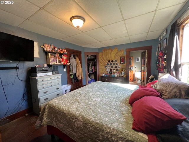 bedroom featuring a closet, a drop ceiling, and baseboards